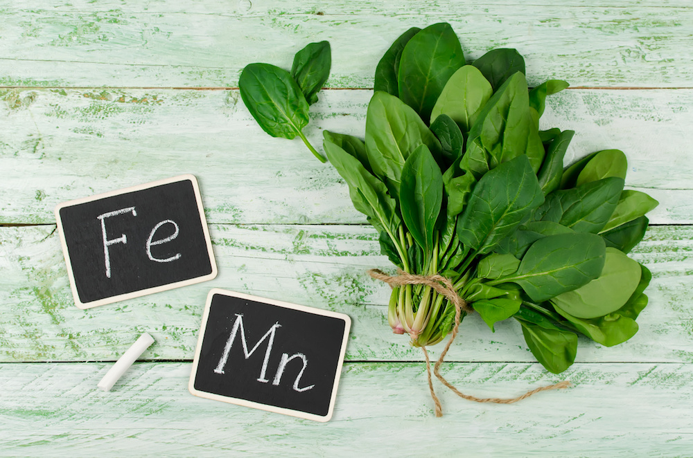 Fresh bunch of spinach on a wooden background. Spinach is rich in vitamin C, A, manganese and iron